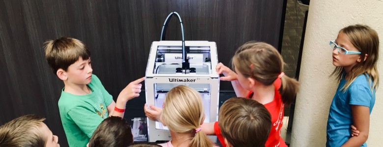 A group of children looking at a 3D printer