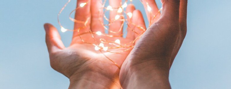 Cupped hands holding illuminated fairy lights