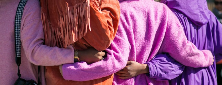 The backs of four women hugging