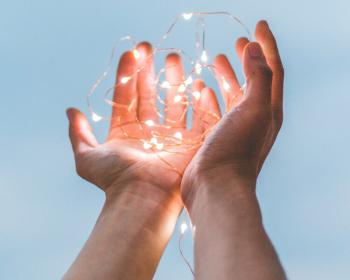 Cupped hands holding illuminated fairy lights