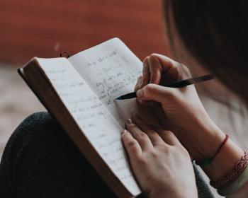 Looking over the sholder of a person writing in a journal